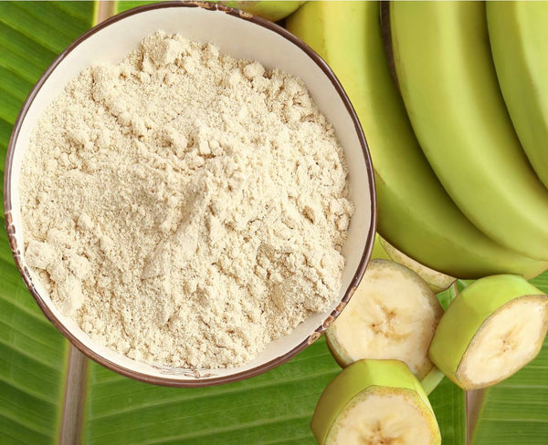 Green banana flour in bowl with green bananas